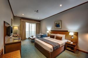 a hotel room with a bed and a living room at Orchid Hotel Al Barsha "Formerly Golden Tulip Hotel Al Barsha" in Dubai