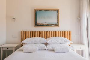 a bed with white pillows and a picture on the wall at MUTE Hostel Porto Covo in Porto Covo