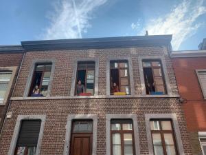 eine Gruppe von Menschen, die aus den Fenstern eines Backsteingebäudes blicken in der Unterkunft Espace Douffet - Un havre de paix en pleine ville in Lüttich