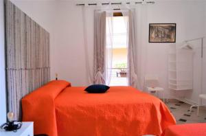 1 dormitorio con cama de color naranja y ventana en La casa del mugnaio 2019, en Castronuovo di Sicilia