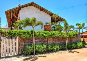 a building with palm trees and a fence at Pousada Barra del Mundo in Barra Grande