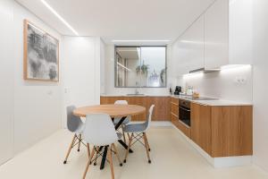 a kitchen with a wooden table and white chairs at Lidador 116 Apartments in Vila do Conde