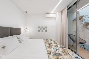 a white bedroom with a bed and a chair at Lidador 116 Apartments in Vila do Conde