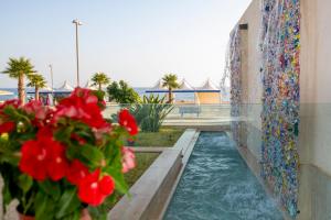 una piscina d'acqua accanto a un muro con fiori di Giardini sul Mare - Mazara del Vallo a Mazara del Vallo