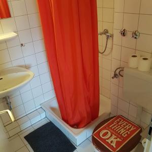 a shower with an orange shower curtain in a bathroom at Stadtnah an der Förde 104 in Flensburg