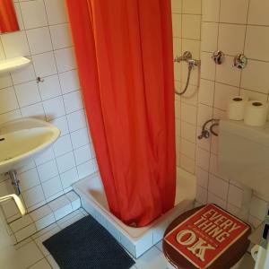 a shower with an orange shower curtain in a bathroom at Stadtnah an der Förde 104 in Flensburg +8 photos