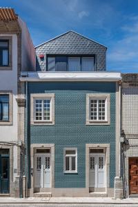 a blue brick house with white windows on a street at Lidador 116 Apartments in Vila do Conde