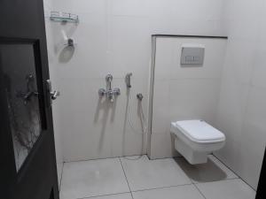 a white bathroom with a shower and a toilet at Muziris Manor Residency in Cochin