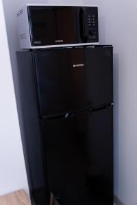 a microwave sitting on top of a black refrigerator at Apartament ALESSIA in Drobeta-Turnu Severin