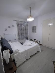 a white bedroom with a bed and a chandelier at Le Casette di Franco & Anna in Assisi