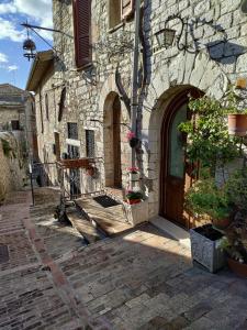 un antiguo edificio de piedra con una puerta de madera y flores en Le Casette di Franco & Anna en Asís