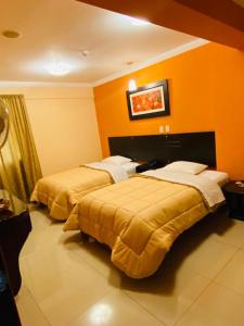 2 camas en una habitación con paredes de color naranja en Royal Garden Hotel, en Lima