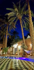 a resort with palm trees and a swimming pool at night at Riad Dar Sofian in Zagora