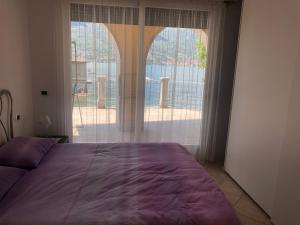 een slaapkamer met een paars bed en een groot raam bij Cottage il Cigno con accesso al lago - Como Lake in Dervio