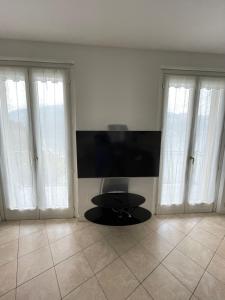 a living room with a tv and three windows at Cottage il Cigno con accesso al lago - Como Lake in Dervio