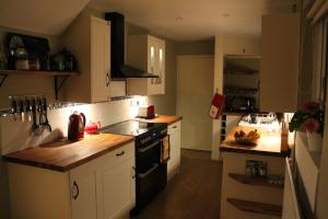 a kitchen with white cabinets and a black stove top oven at Llys y Coed in Brechfa +6 photos