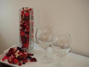 two wine glasses and a vase with flowers on a table at Hotel Marie in Mamaia