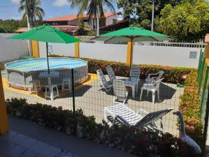 eine Terrasse mit einem Tisch, Stühlen und Sonnenschirmen in der Unterkunft Casa de Praia Veraneio in Maceió