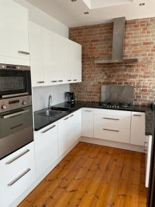 a kitchen with white cabinets and a brick wall at Uroczy apartament 97m2 w samym centrum Wrocławia in Wrocław