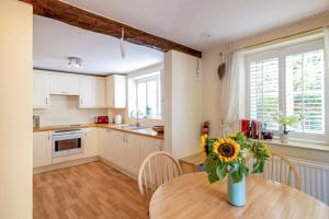 a kitchen with a table and a vase with a sunflower on it at The Old Stables in Tetbury