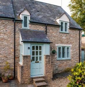 a brick house with a blue door and windows at The Old Stables in Tetbury