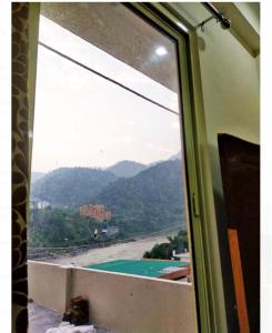 una finestra con vista su un fiume e sulle montagne di Shiv Gauri Home Stay a Rishikesh Altre 3 foto