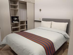 1 dormitorio con 1 cama blanca grande y armario en La Casa de Justi, en Huancayo