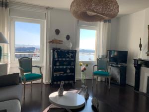a living room with a couch and chairs and a tv at Appartement Villa Chausey, vue sur le port in Granville