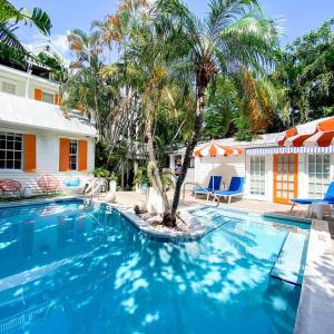 a swimming pool with a palm tree in front of a house at Marreros Guest Mansion - Adult Only in Key West