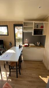 a kitchen with a white table and a table and a room at EcoKub T3 Proche plages Lacs in Soustons