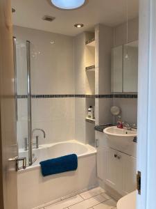 Baño blanco con bañera y lavamanos en Henley Town Rooms, en Henley on Thames