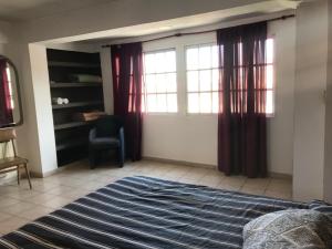 1 dormitorio con cama, ventana y silla en Departamento Belgrano III en Salta