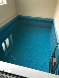 a large swimming pool with blue tiles in a bathroom at Villa SOFI in Lviv