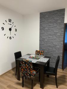a dining room with a table and a clock on the wall at Happy M&S 2 in Šabac