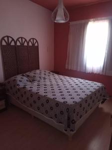 1 dormitorio con 1 cama grande con edredón blanco y ventana en Rufina Alojamiento en Playa Unión