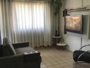 een woonkamer met een bank en een televisie bij ACONCHEGO BARRAVENTO in João Pessoa