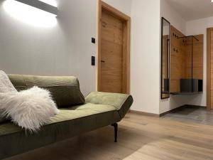 ein Wohnzimmer mit einer grünen Couch und einer Holztür in der Unterkunft HAUSZEIT APPARTEMENTS in Haus im Ennstal