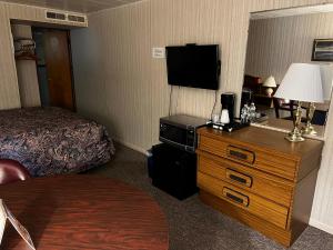 um quarto de hotel com uma cama e uma cómoda com uma televisão em Hopwood Motel em Uniontown