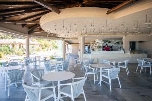 un restaurante con mesas y sillas blancas y un bar en Villaggio Il Gabbiano, en Capo Vaticano