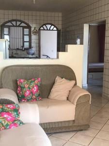 a couch with pillows sitting in a living room at Jacaraipe ES -Lar de Praia casa temporada in Jacaraípe