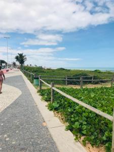 a woman walking down a sidewalk next to a fence at Jacaraipe ES -Lar de Praia casa temporada in Jacaraípe