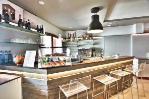 a restaurant with a counter with stools and a bar at Aparthotel Ponza in Lignano Sabbiadoro