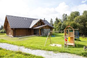 uma cabana de madeira com um parque infantil e uma casa em Luxusní srub až 24 lůžek - Sruby-lipno em Frymburk