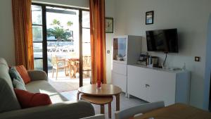 a living room with a couch and a tv and a table at Bungalow Tetir in Caleta de Fuste in Caleta De Fuste