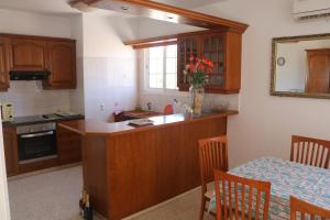 una cocina con armarios de madera y una mesa con un jarrón de flores en Ria Beach Sea View Apartment, en Pyla