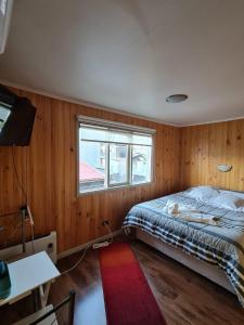 um quarto com uma cama, uma janela e um tapete vermelho em La Ruta de Aysén em Coihaique