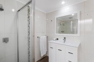 a white bathroom with a sink and a shower at Avondel Motor Inn in Benalla