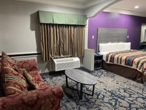 a hotel room with a bed and a couch at Scottish Inn and Suites Alvin in Alvin +44 photos