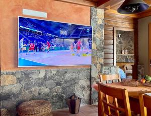 een tv aan de muur met een basketbalwedstrijd erop bij casa rural LA LIMERA con piscina privada in Santa Lucía