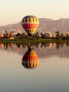 a hot air balloon flying over a body of water at Nile queen Apartments for Rent in Luxor +10 photos